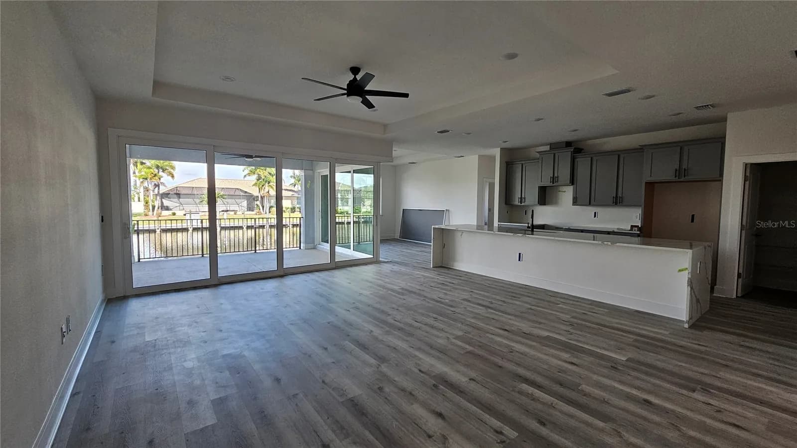 Sala principal abierta a la cocina, con puertas corredizas que dan al lanai y al canal